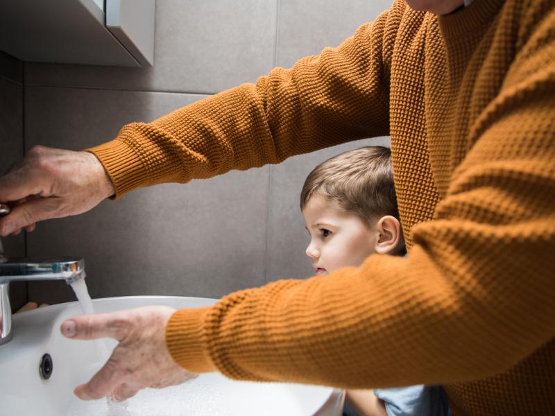 Aikuinen ja pieni lapsi pesemässä käsiä.
