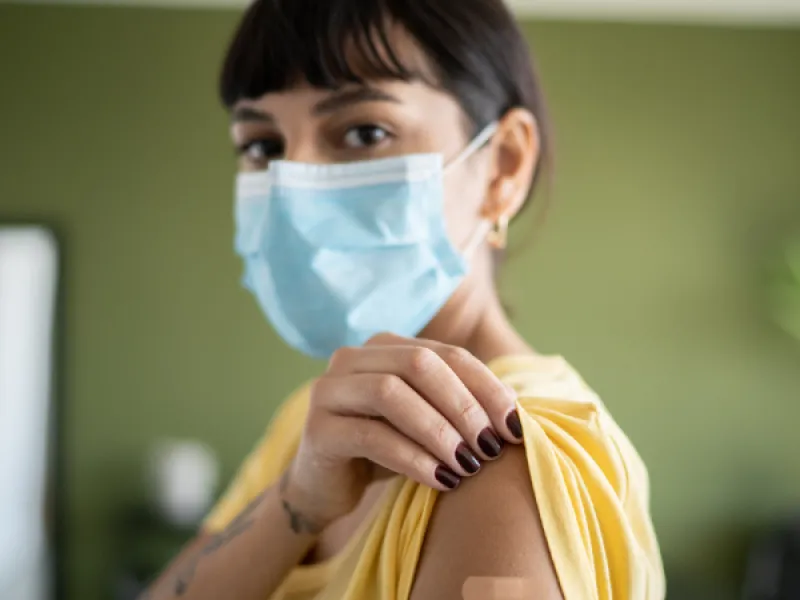 Rokotettu nainen, maski kasvoilla.